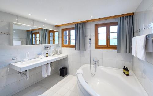 a white bathroom with a tub and a sink at Hotel Stoffel - adults only in Arosa