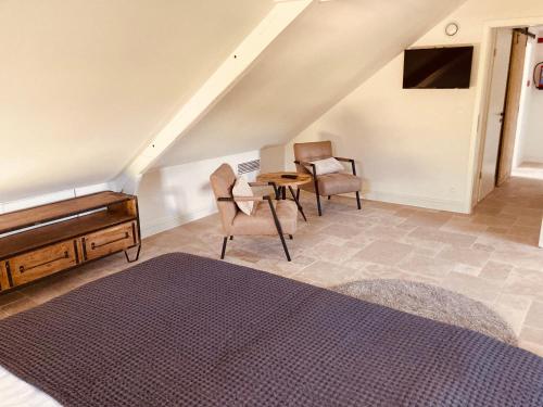 a bedroom with a bed and chairs and a table at De Molenhoeve in Voeren