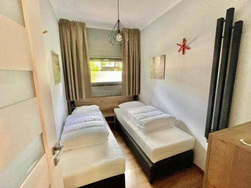 mały pokój z 2 łóżkami i oknem w obiekcie Cosy Tiny Lodges - vakantiepark Kempenbos w mieście Diessen