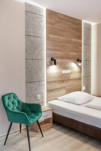 a bedroom with a bed and a green chair at Kamienica Morska Gdynia in Gdynia