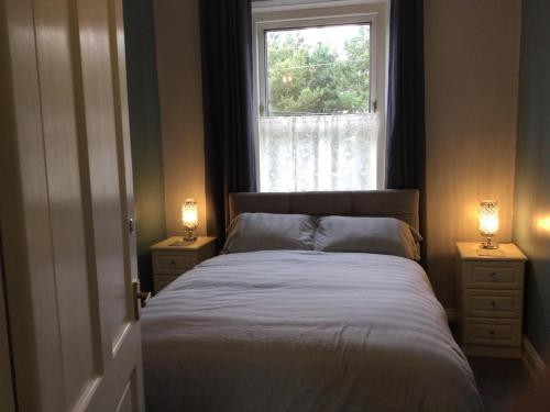 een slaapkamer met een bed en een raam met 2 lampen bij The Old School House in Durham