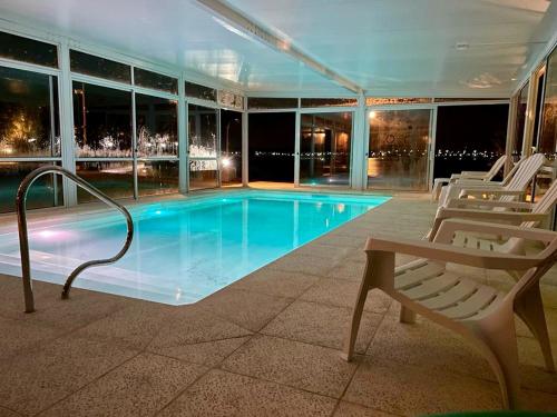 a swimming pool with two chairs and a bench at Apart Hotel Terrazas de San Francisco in Piriápolis