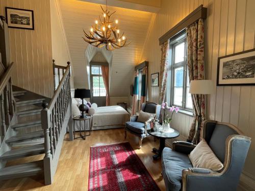 a living room with a chandelier and a stair case at Hofslund Fjord Hotel in Sogndal