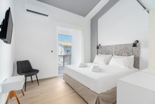 une chambre blanche avec un lit et une chaise dans l'établissement COSTA VASIA Boutique Apartments, à Vrahati