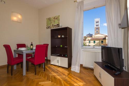 een woonkamer met een tafel en rode stoelen en een televisie bij Residence il Duomo in Lucca