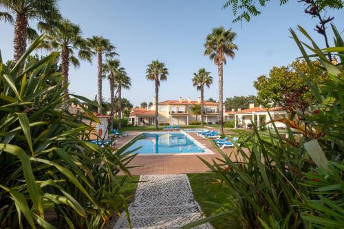 a resort with a pool and palm trees at Fantastic T3 Sebastião in Casal da Lagoa Seca