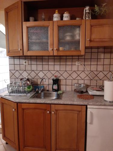 a kitchen with wooden cabinets and a sink at Comfy Apartment near the Sea in Ierápetra