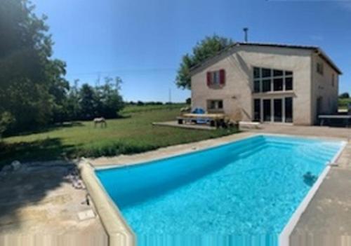 a large blue swimming pool in front of a house at Domaine de Montels in Albias