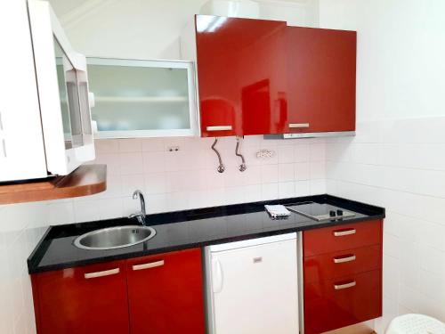 a kitchen with red cabinets and a sink at Mateus Studios in Vila Nova de Milfontes