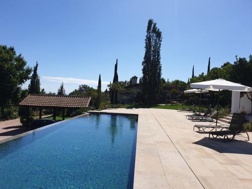 a large swimming pool with chairs and an umbrella at Lalisea in Talaveruela