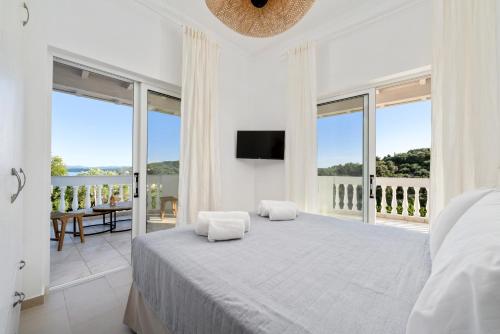 a white bedroom with a large bed and a balcony at Playia Villas III in Petrití