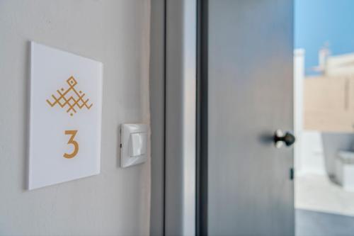 a door with a light switch and a number on it at Nomadic Cozy Rooms in Ermoupoli