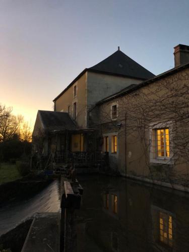 a house with its lights on in the water at Les roulottes du Moulin de Palet in Chartrené