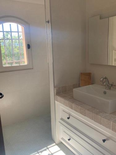 une salle de bain blanche avec un lavabo et un miroir dans l'établissement Villa Le B, à Cogolin