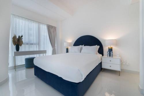 a white bedroom with a large bed and a window at Blue dream apartment with Harbour view in Dubai Marina in Dubai