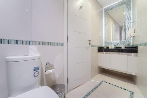 a white bathroom with a toilet and a mirror at Blue dream apartment with Harbour view in Marina in Dubai