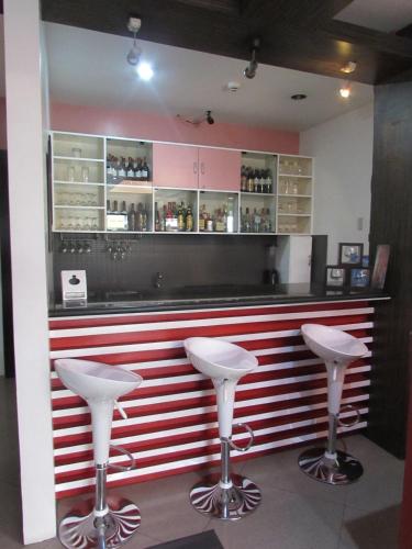 a red and white bar with two white stools at Oyster Plaza Hotel in Manila