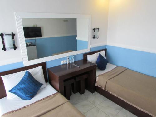 a hotel room with two beds and a mirror at Oyster Plaza Hotel in Manila
