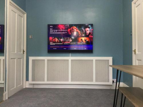a flat screen tv hanging on a blue wall at The Old School House in Durham