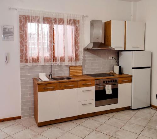 cocina con armarios blancos, fogones y nevera en Maroudas Stavros Apartments, en Vathí - Ítaca