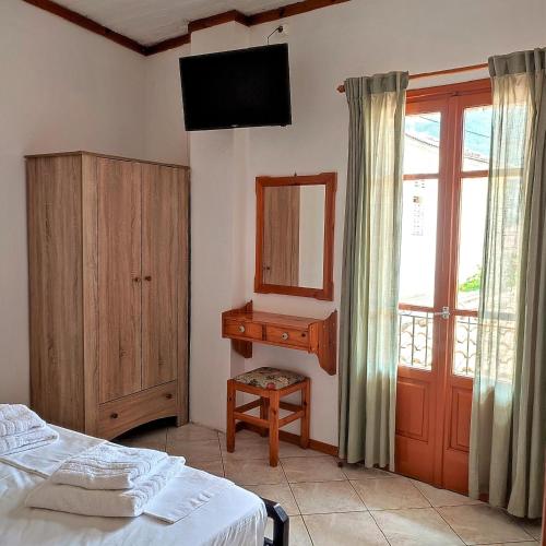 a bedroom with a bed and a mirror and a window at Maroudas Stavros Apartments in Vathi, Ithaka