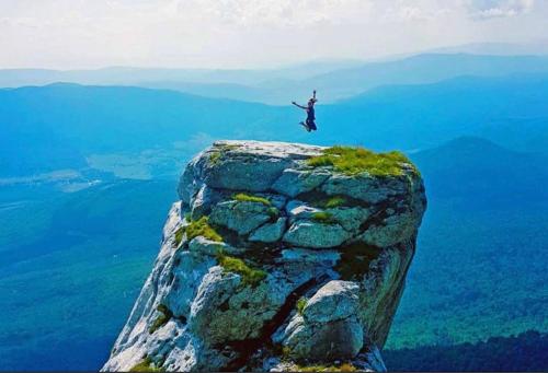 a man is jumping off of a rocky mountain at Hedgehog's Home in Korenica