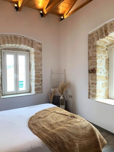 a bedroom with a large white bed with two windows at Dizen Spartochori in Meganisi