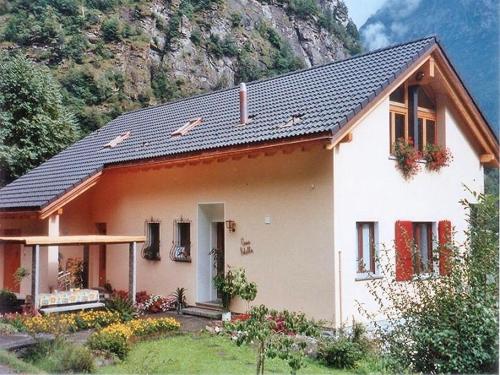 een klein wit huis met een berg op de achtergrond bij Appartamento N. 6 Casa Betulla in Sonogno