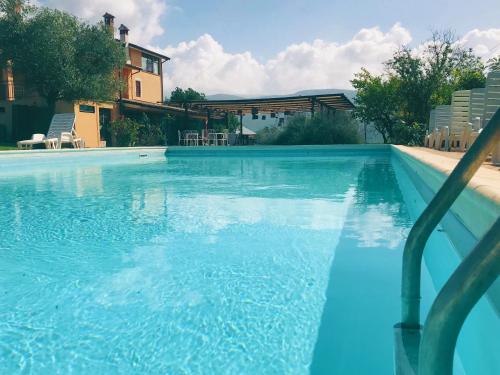 una piscina de agua azul frente a una casa en Tenuta delle Acque, en Acquasparta