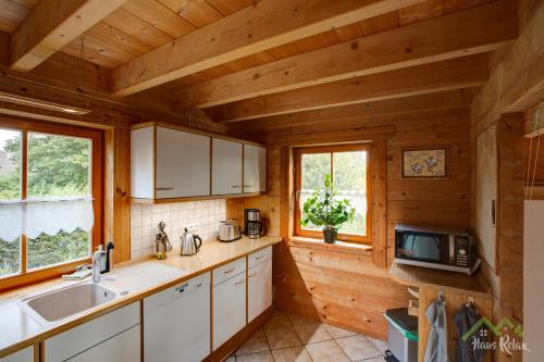 a kitchen in a log cabin with a sink and a microwave at haus-relax - no business b00king - no fitters in Bittstädt
