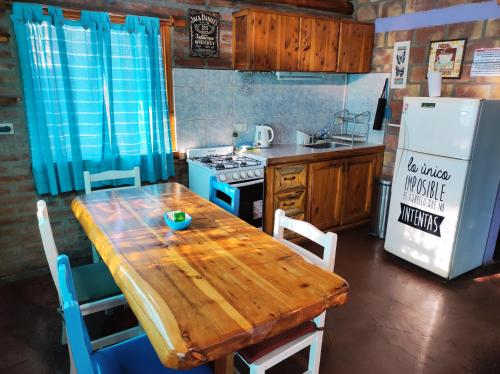a kitchen with a wooden table and a refrigerator at Cabañas Los Lúpulos in El Bolsón