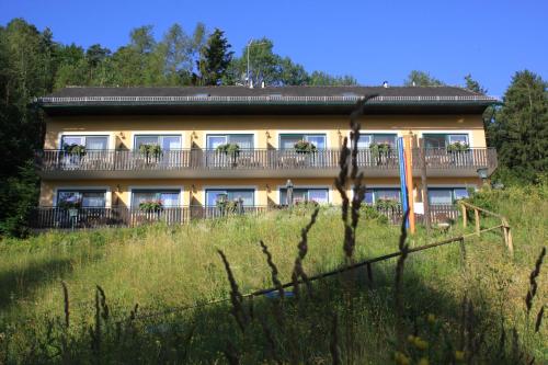 a large house on a hill with a fence at Pension Waldhof am Stubenbergsee in Stubenberg