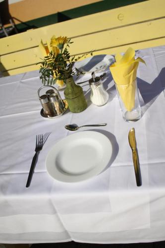 a white table with a white plate and utensils at Pension Waldhof am Stubenbergsee in Stubenberg