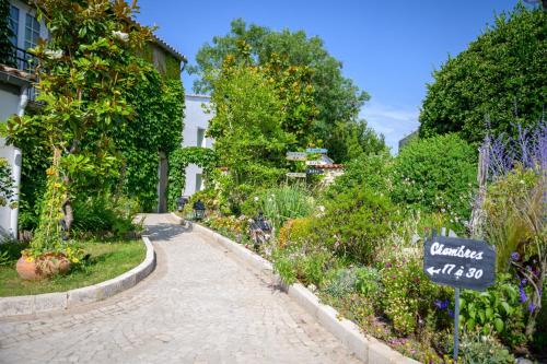 a cobblestone walkway in a garden with flowers at Hôtel Le Peu Breton in Sainte-Marie-de-Ré