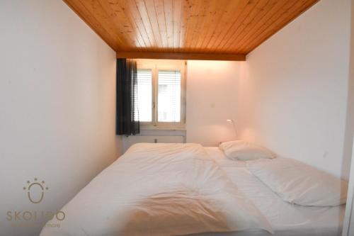 1 dormitorio con cama blanca y techo de madera en Apartment A im Grünen, Mörel Breiten, en Mörel