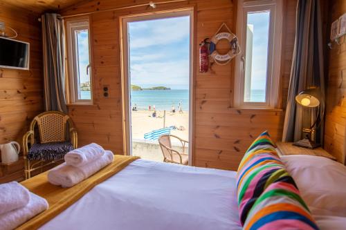 um quarto com uma cama e vista para a praia em Tolcarne Beach Cabins em Newquay