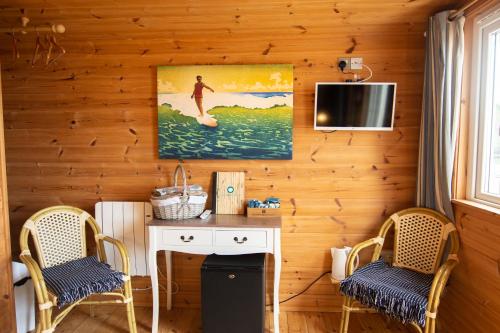 ニューキーにあるTolcarne Beach Cabinsの椅子2脚、デスク、テレビが備わる客室です。