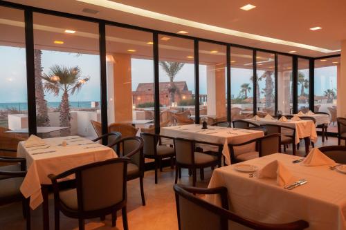 a restaurant with tables and chairs and windows at Vincci Dar Midoun in Djerba