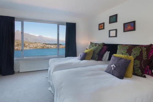 two beds in a room with a large window at Star Lane by Amazing Accom in Queenstown
