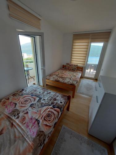 a bedroom with two beds and a window with roses at MANONI APARTMANI in Kumbor