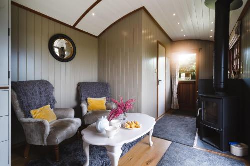 sala de estar con sofá, mesa y silla en Hooting Owl Retreat, en Wheddon Cross