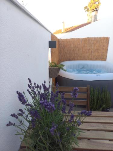 a bath tub sitting on a patio with purple flowers at Casa do Ferreiro by Valada Village in Valada