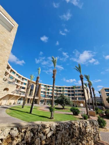 a group of palm trees in front of a building at The MUSIC suite - Neot Golf Caesarea in Caesarea