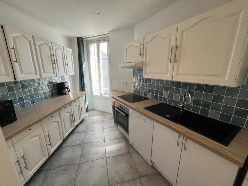 une cuisine avec des armoires blanches et un évier dans l'établissement Bel appartement Cannes (plage, palais, shopping, tout à pied), à Cannes