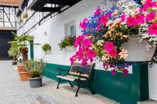 a bench sitting in front of a building with flowers at Thüringer Tannenhof Ferienwohnungen in Geroda