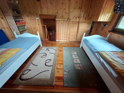 two beds in a room with wooden floors and wooden walls at Zacisze in Uście