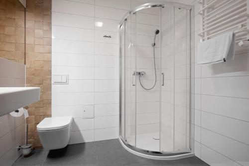 a white bathroom with a shower and a toilet at Holimo Hotel in Stronie Śląskie
