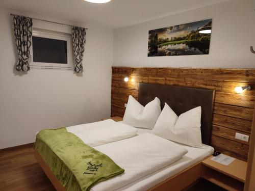 una camera da letto con un grande letto con lenzuola bianche di Appartement Kuschelzeit Jansenbichl a Wagrain