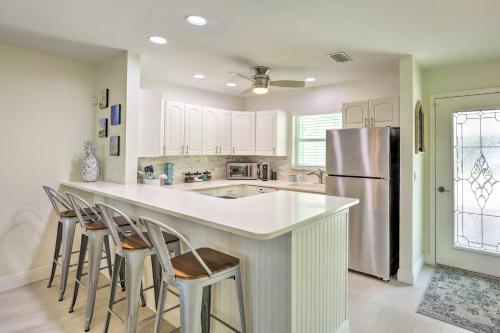 a kitchen with a island with bar stools and a refrigerator at Boat Owners Paradise Jensen Beach Home with Dock! in Jensen Beach