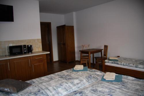 a room with two beds and a kitchen and a table at Miętusia Przystań - Wynajem Pokoi in Ciche